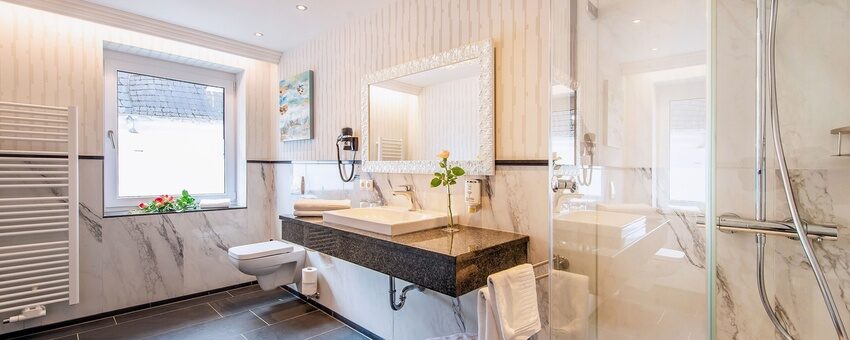 Das Bild zeigt ein modernes Badezimmer mit Dusche Waschbecken und auch einem Handtuchtrockner