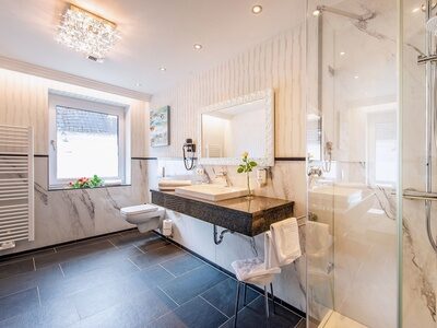 Das Bild zeigt ein modernes Badezimmer mit Dusche Waschbecken und auch einem Handtuchtrockner