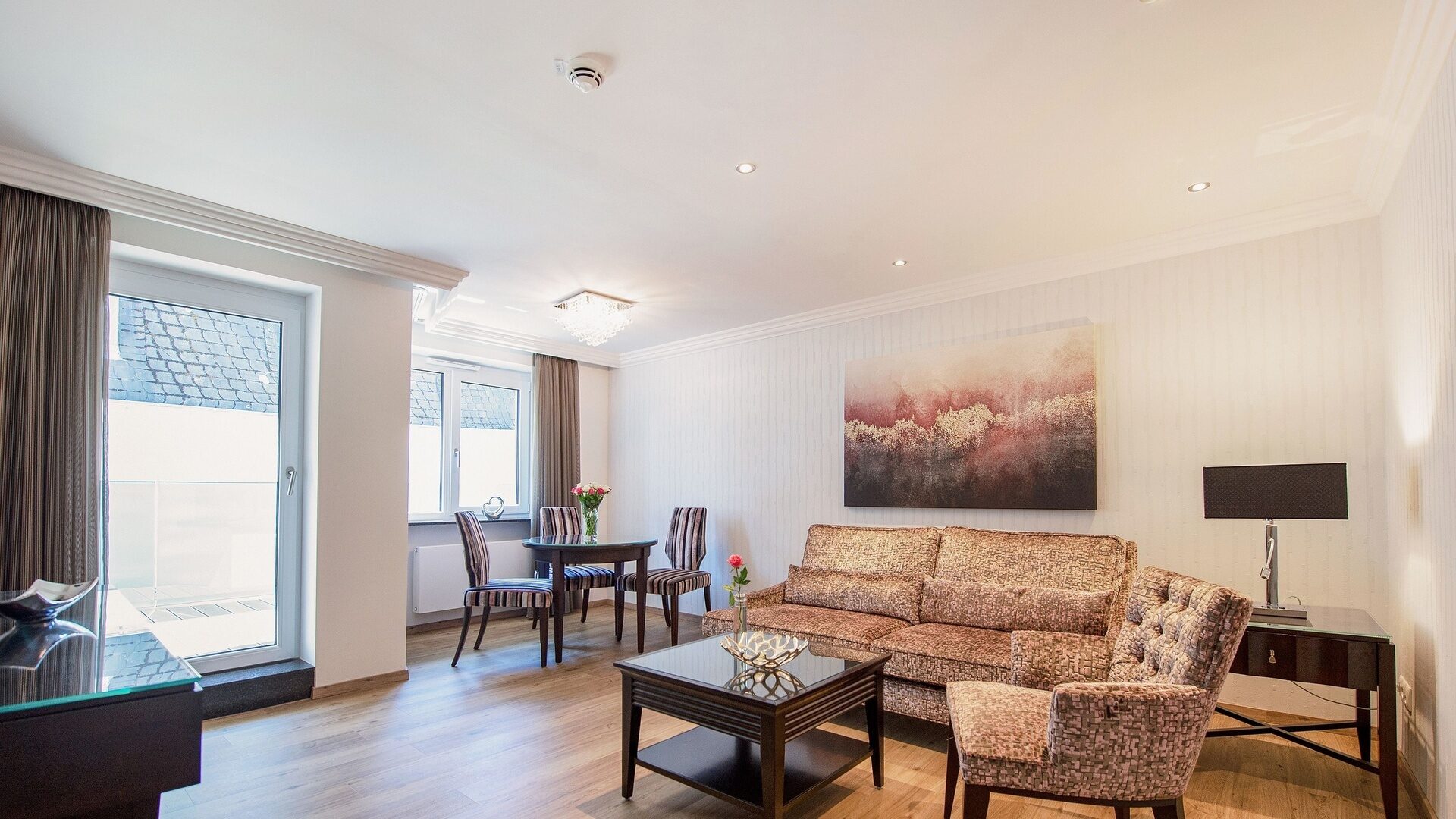 Der Wohnraum in einem Appartement der Kategorie 4 im Neubau des Hotels Residenz am Rosengarten bietet unter anderem einen Tisch mit Stühlen und eine Couch