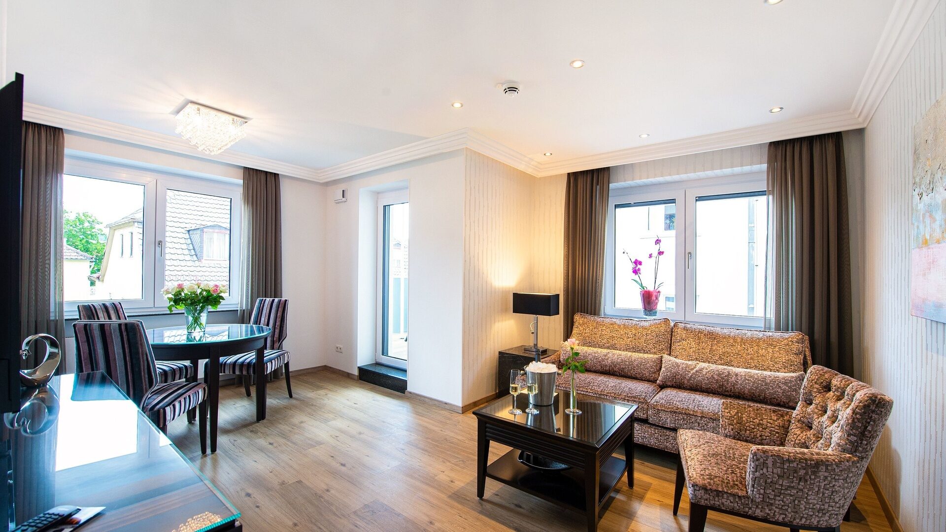 Gemütlicher Wohnbereich im Hotelzimmer mit edlem Holzboden und stilvoller Sitzgruppe in der Residenz am Rosengarten